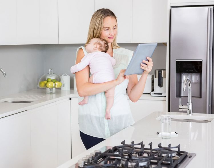 Frau hält Baby und Tablet