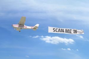 Flugzeug mit Werbebanner, auf dem ein QR-Code abgebildet ist.